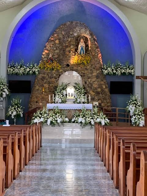 The grotto altar of Our Lady of Lourdes Parish Church, dressed in white flowers